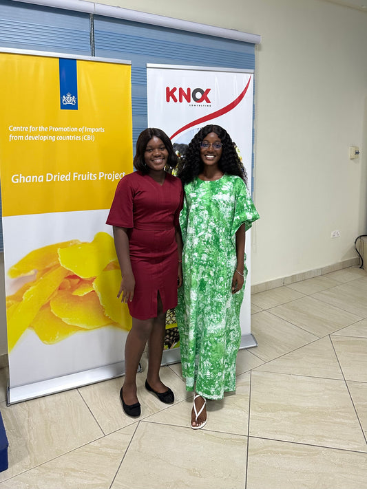 Alice and Eunice stand indoors in front of two pull up banners with images and text referring to dried fruit and the CBI program